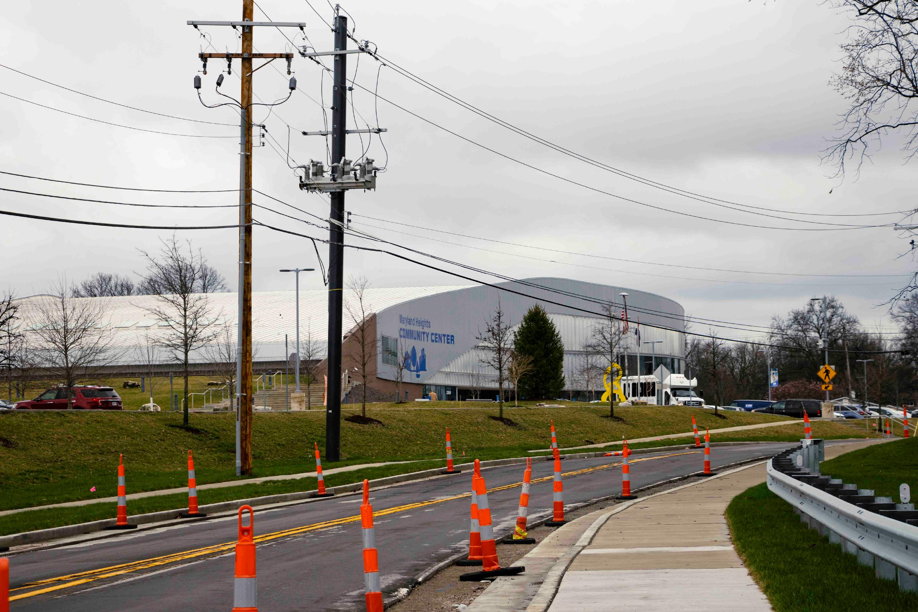 A photo taken on the sidewalk of McKelvey Road shows many traffic cones, with the Maryland Heights Community Center in the background on a cloudy day